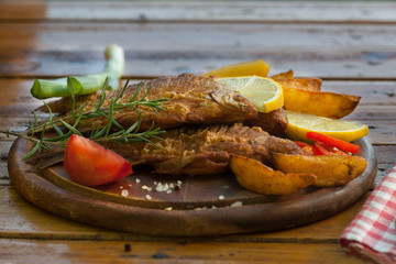 Fried Fish with potato on wooden board. Healthy food with omega 3 unsaturated fatty acid. Fish and chips.