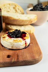 Close up view on grilled camembert with blackberry jam, nuts and chiabatta on grey background. Copy space. Cheese. Tasty food for lunch. Soft focus. Food for wine