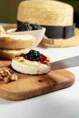 Close up view on grilled camembert with blackberry jam, nuts and chiabatta on grey background. Copy space. Cheese. Tasty food for lunch. Soft focus. Food for wine