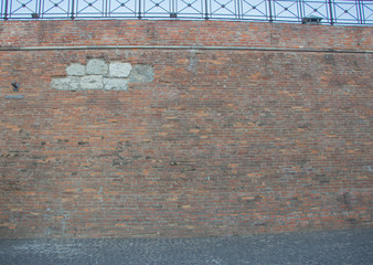 Brick wall overgrown with grass and moss. Pledged window with red brick..