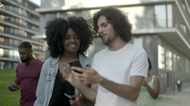 Cheerful friends looking at smartphone during stroll. Smiling users testing new application on device. Technology concept