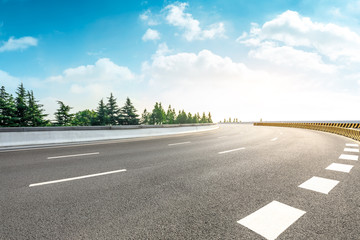 Fototapeta premium Country asphalt road and green woods nature landscape at sunset
