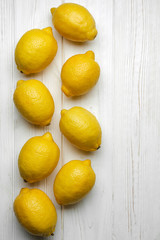 fresh whole yellow lemons on white wood background with space for text. top view