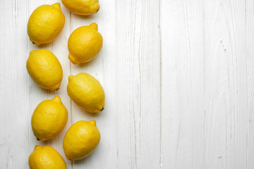 fresh whole yellow lemons on white wood background with space for text. top view