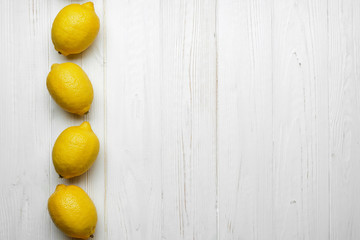 fresh whole yellow lemons on white wood background with space for text. top view