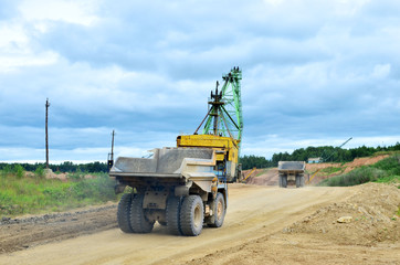 Obraz premium Big yellow dump truck working in the limestone open-pit. Loading and transportation of minerals in the dolomite mining quarry. Belarus, Vitebsk, in the largest i dolomite deposit, quarry 