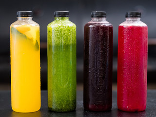 Homemade beverage assortment. Bottles with yellow citrus, green cucumber lemonade, berries kompot, currant juice.