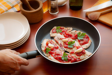 Preparation of pork chops with tomato, garlic, parsley, olive oil and pepper, in a pan
