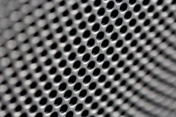 Abstract close up of a metal surface filled with small holes.