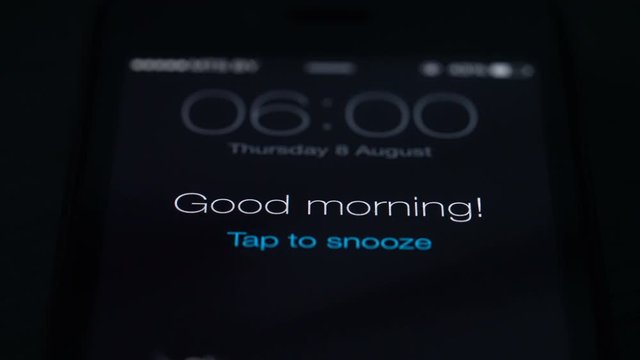 Good morning alarm clock on the phone in the dark room, close-up