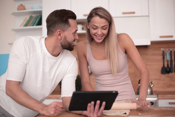 Young couple surfing the web with tablet at home kitchen