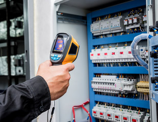 Technician use infrared thermal imaging camera to check temperature at fuse-box - obrazy, fototapety, plakaty