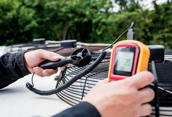 Technician use hand-held anemometer measuring air flowing measurement, wind speed and pressure.