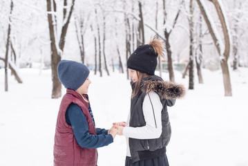 Fototapeta na wymiar brother and sister students having fun after school on a snowy day. a schoolgirl and a schoolboy playing together in winter
