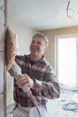 Plasterer smoothing interior wall of new homes with machine