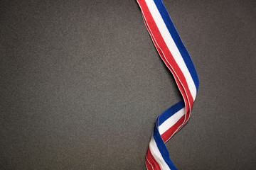 Symbol of the British national tricolor flag twisted ribbon on black background above case space