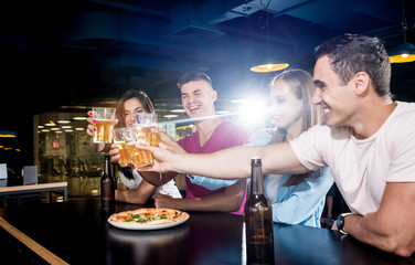 Cheerful friends in the pub. Drinking beer, wine and whisky, talking, having fun.