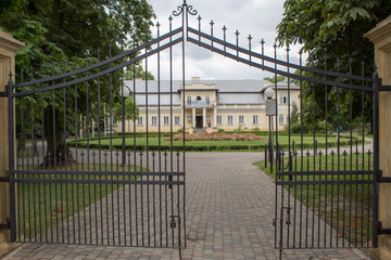 Fototapeta premium Urban Polish landscape - the building of the museum-estate and a beautiful park with a green lawn and trees.