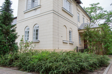 Urban Polish landscape - the building of the museum-estate and a beautiful park with a green lawn and trees.
