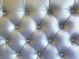 Silver leather upholstery screed tightened with rhinestone buttons. Сhesterfield style quilted upholstery backdrop close up. Capitone pattern texture background