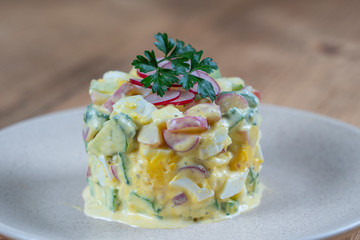 Delicious salad with cucumber, radish and egg with cream sauce in a plate on wooden background. Healthy food, close up