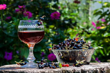 Blackcurrant wine with berries in avza glass from an old wooden table