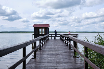 Photo of a beautiful river pier with a wooden walkway in the summer on the lake. Made outdoors in summer.