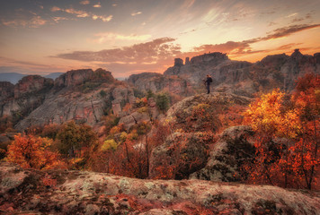 Beautiful girl shoots a sunset at Belogradchik rocks. Magnificent panoramic sunset view of the Belogradchik rocks in Bulgaria. Autumn scene.