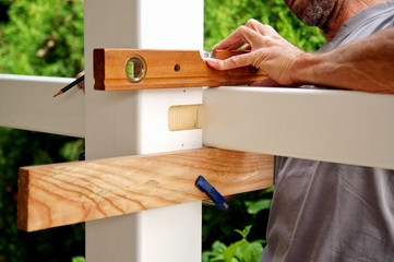 carpentry joints. Wood post, rabbet joint. Mounting the carport. carpenter using a spirit level to...