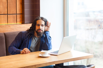 What you say? Interesting handsome young adult man freelancer in casual style sitting in cafe and talking with his friend in laptop, trying to listen holding hand near ear. Indoor, lifestyle concept