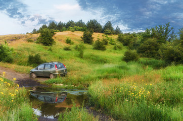 Summer landscape, car in a beautiful meadow near the water