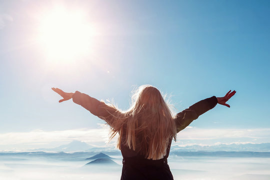Beautiful happy woman enjoying mountains landscape with  outstretched raised arms to the sky