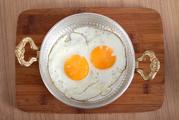Eggs cooked in oil in a high-angle copper dish