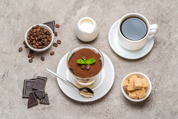 Classic tiramisu dessert in a glass, coffee, chocolate, cream and sugar on concrete background
