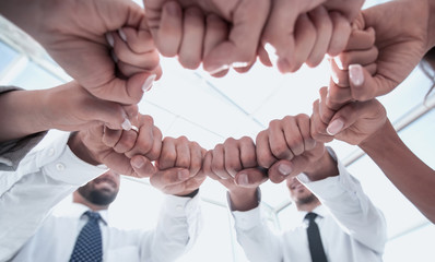 close up. employees of the company forming a circle out of their fists