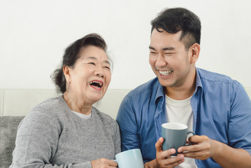Fototapeta premium Asian mother and her son talking and drinking at home, lifestyle concept.