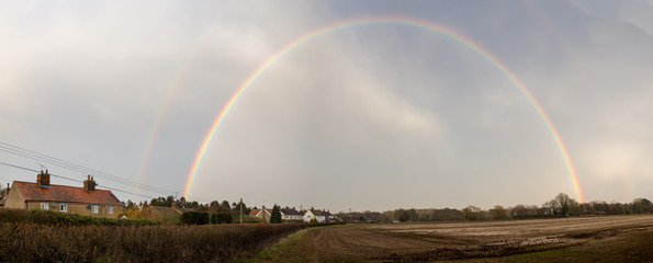 A big arching rainbow over a small countryside Suffolk village