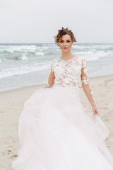 Fototapeta na wymiar Portrait of a beautiful bride on the beach in windy weather