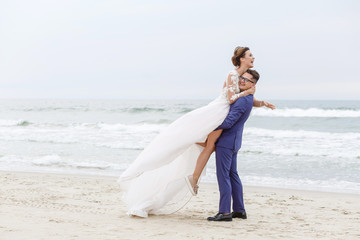 Fototapeta na wymiar The groom whirls his bride on the beach