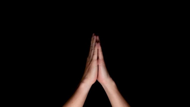 Hands joining together for surya namaskar on a black background, medium shot