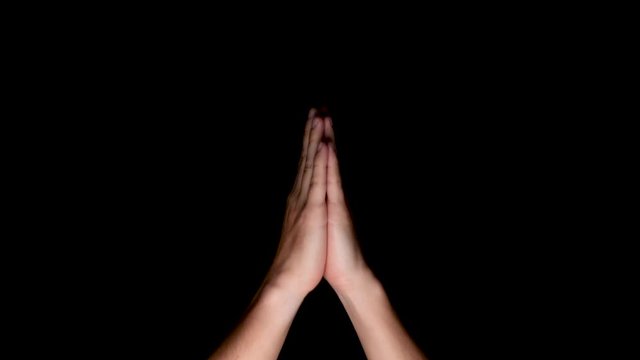Yoga namaste hand symbol for praying on a black background, medium shot