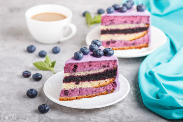 Homemade cake with souffle cream and blueberry jam with cup of coffee on a gray concrete  background. side view.