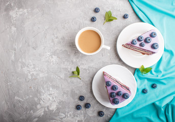 Homemade cake with souffle cream and blueberry jam with cup of coffee on a gray concrete  background. top view.