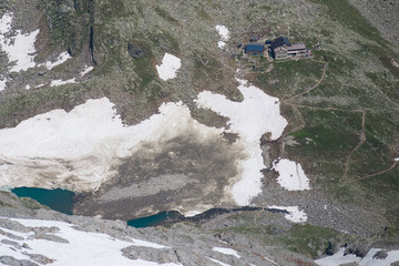 High altitude mountain landscape with hut and small glacier lakes in the Alps
