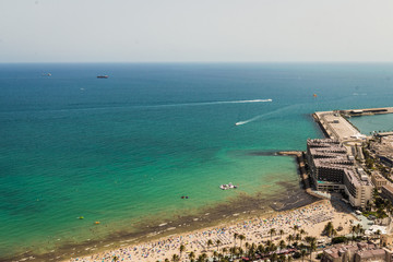 Crowded beach with a blue Mediterranean sea seen from a hill
