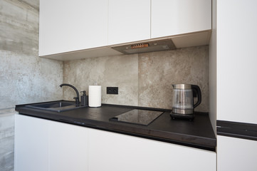 white minimalist kitchen with black countertop and sink