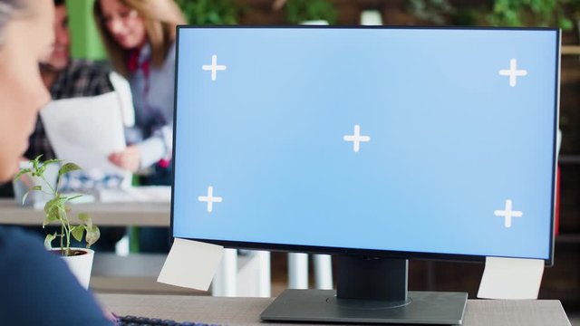 Caucasian business woman typing on her computer in the office. Mock-up display. Coworkers in the background.