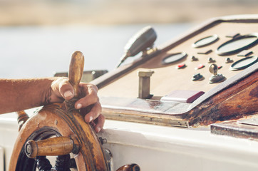 Hands of the captain holding the wheel on the deck of the ship