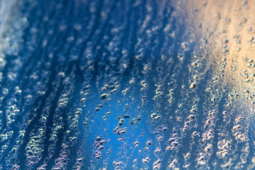 Blue ice and water drops on winter glass macro shot with shallow depth of field