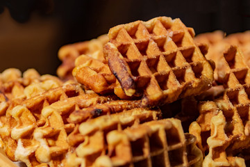 Close up of rustic traditional waffle at street food festival. Outdoor cooking service gastronomy and takeaway food concept